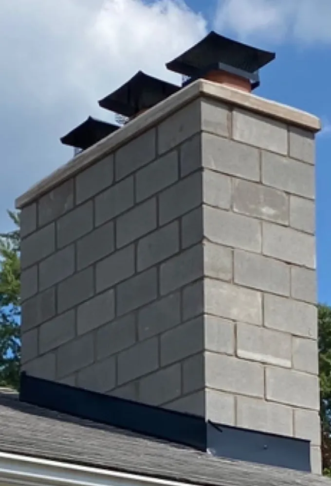 Rebuilt gray block chimney with new crown, flashing and three flue caps