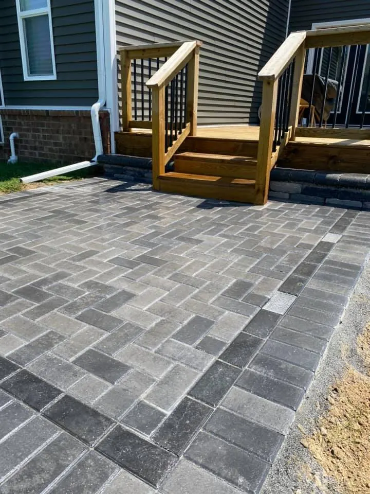 Gray paver patio beside a deck, completed by It's The Brick Guys in Metro Detroit