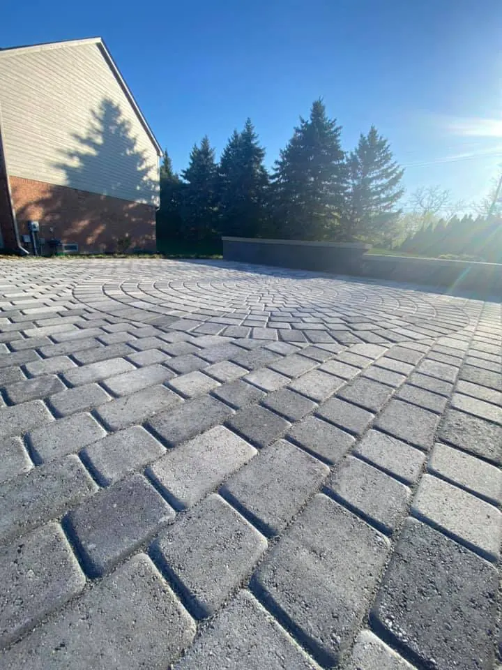 Gray paver patio with circle pattern and seat wall, completed by It's The Brick Guys in Metro Detroit