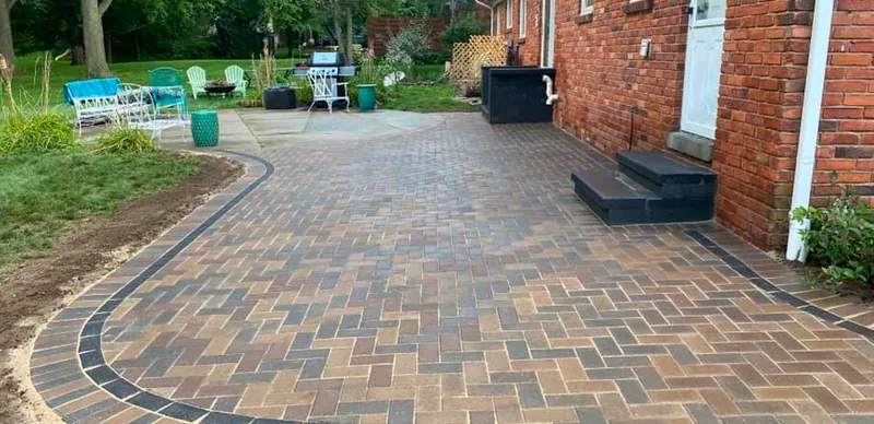 New herringbone paver patio with a charcoal border and steps to the house