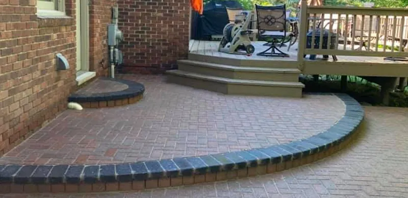Repaired herringbone paver patio with a rebuilt charcoal curved border