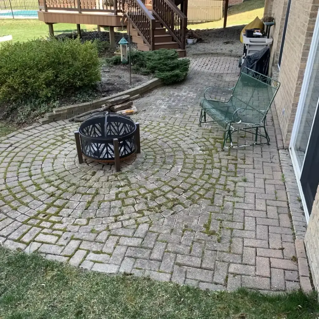 Faded circular paver patio with weeds in Sterling Heights, MI before restoration