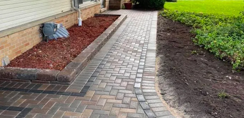 New paver walkway with a charcoal border along a garden bed