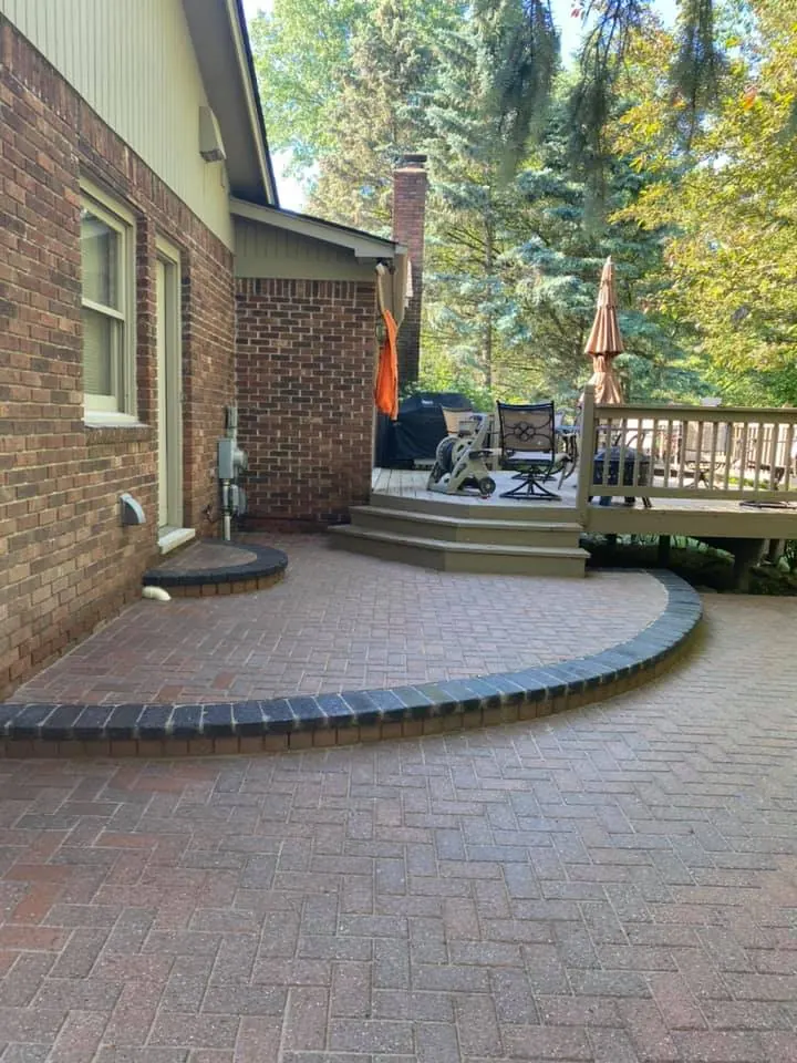 Round brick paver patio by the deck, completed by It's The Brick Guys in Metro Detroit